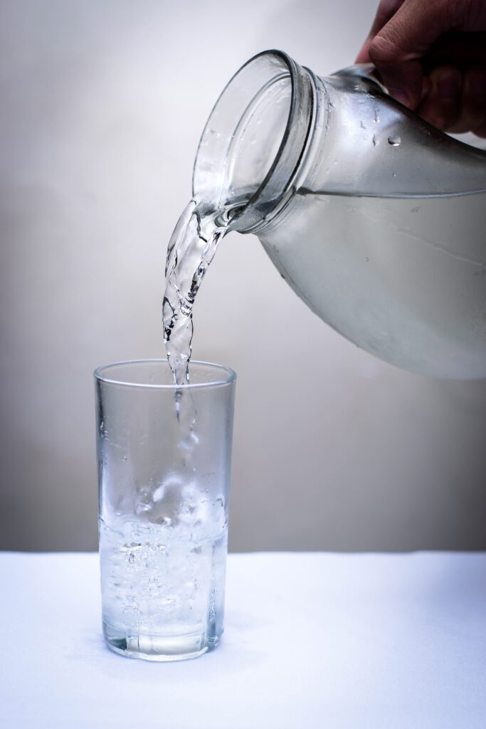 Rent vann helles fra en mugge og over i et glass.